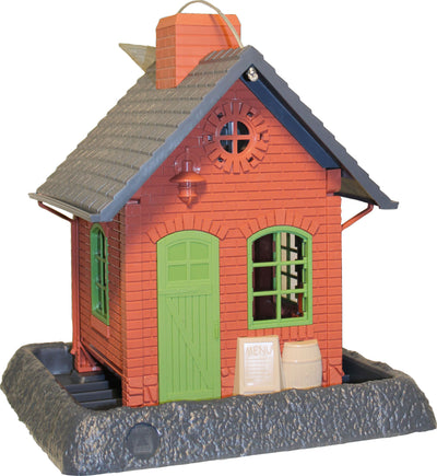 Red brick bird feeder shaped like a pub with green door and windows, menu sign, and barrel on a stone base.