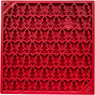 Close-up of a red plastic cookie cutter tray with Christmas tree shapes, one featuring a small tree with dots.