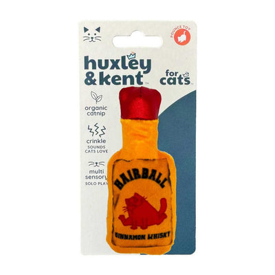 Packaged Huxley & Kent cat toy shaped like a bottle with red cap, orange body, and cinnamon whisky label.