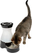 A black and white Petsafe Healthy Pet Water Station with a tabby cat drinking from its bowl.